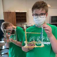 Two students show off their catapult projects